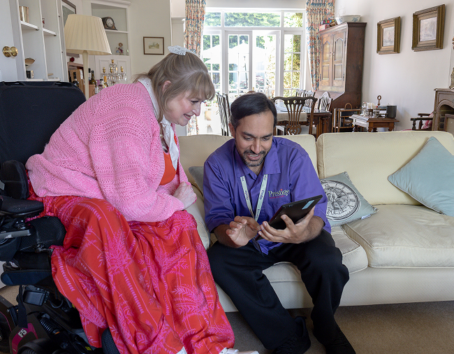 Care professional discussing care with a woman at home using a tablet.