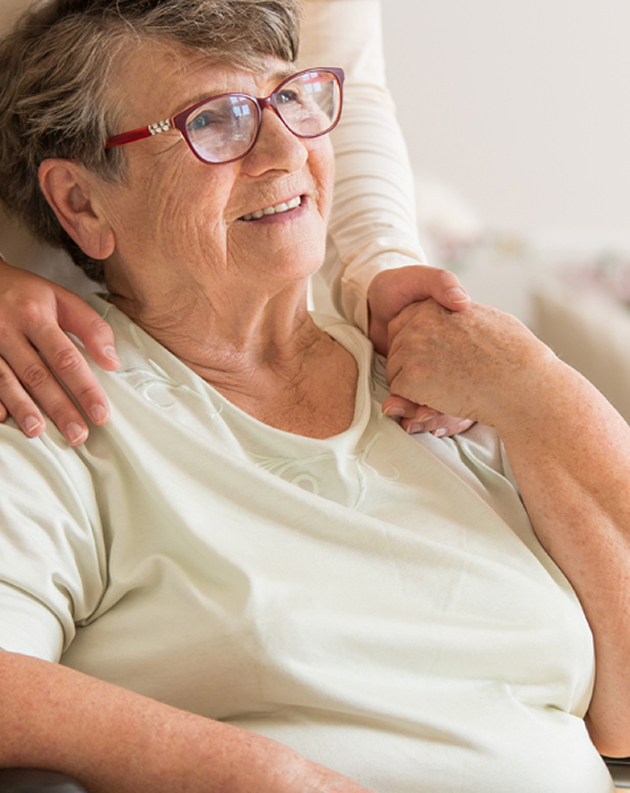 A woman in a wheelchair embraces an older woman, both smiling warmly at the camera