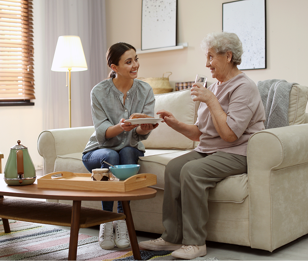 A woman and an older woman sit together on a couch, engaged in conversation and sharing a warm moment