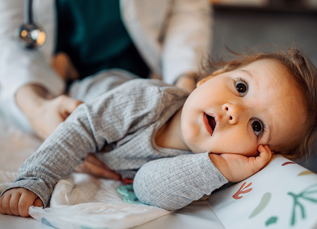 A doctor examines a baby lying on a bed, ensuring the infant's health and well-being