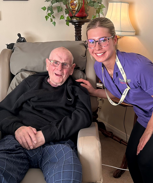 A woman in a purple shirt sits next to an elderly man, both appearing to enjoy each other's company