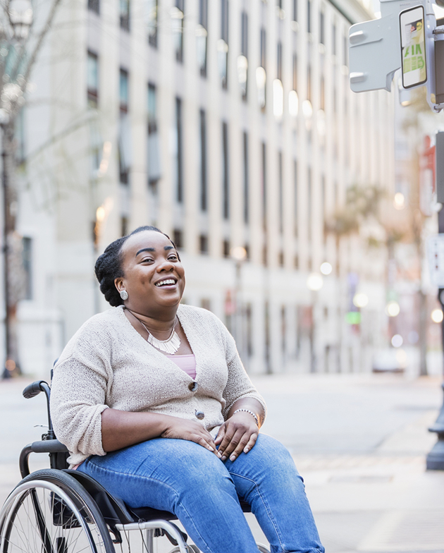 A smiling woman in a wheelchair poses for the camera, radiating positivity and confidence
