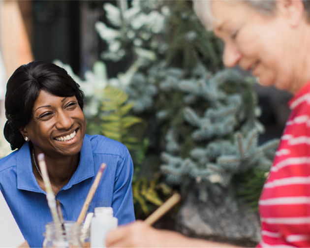 A woman smiles warmly at another woman and a man, creating a friendly and inviting atmosphere