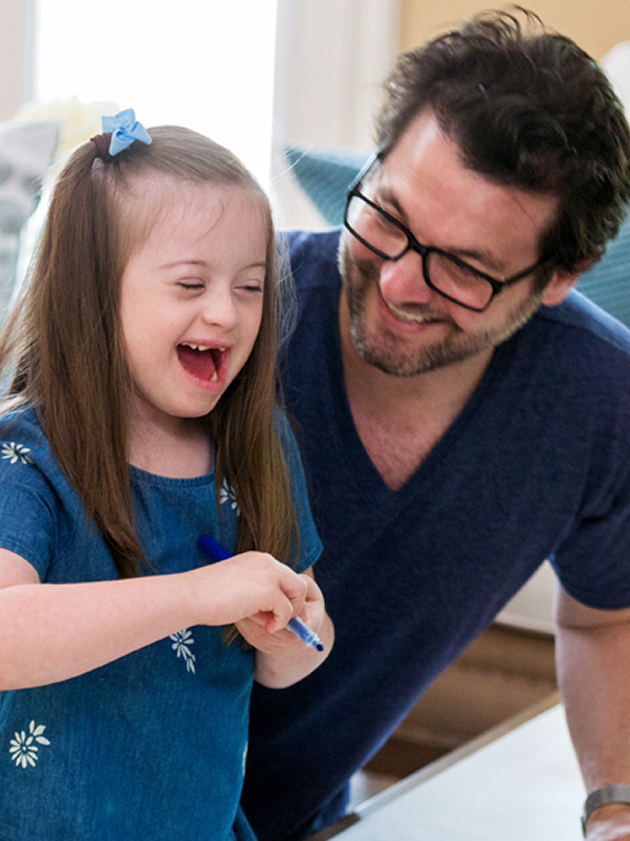 A man and a young girl share a joyful moment, laughing together in a warm and playful atmosphere