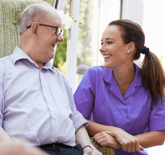 A woman in a purple shirt engages in conversation with an elderly man, both appearing attentive and interested